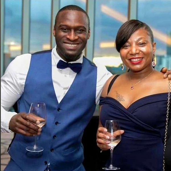 Infinite Caribbean Cuisine logo co-owners pictured dressed smartly and holding glasses of wine